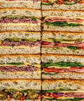 Stack of variously filled sandwiches cut into small pieces on focaccia bread
