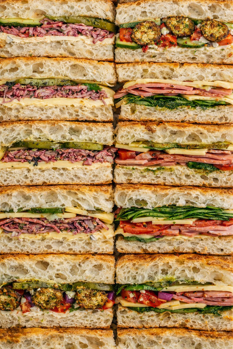 Stack of variously filled sandwiches cut into small pieces on focaccia bread